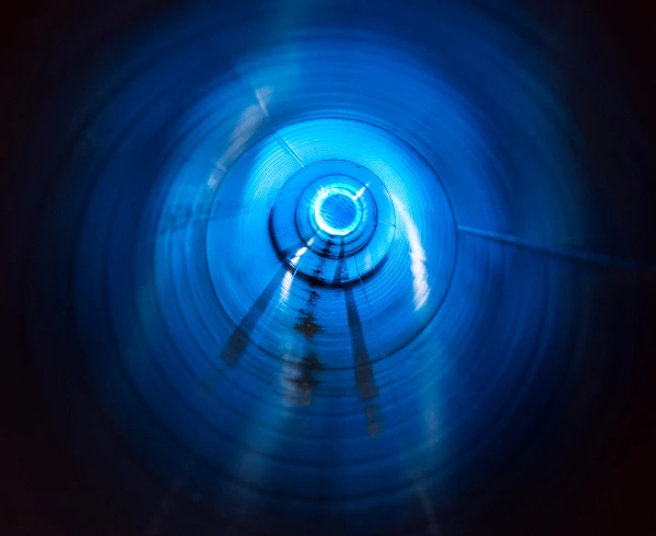 Abstrakt blått ljusspår format som en spiral eller tunnel mot mörk bakgrund.